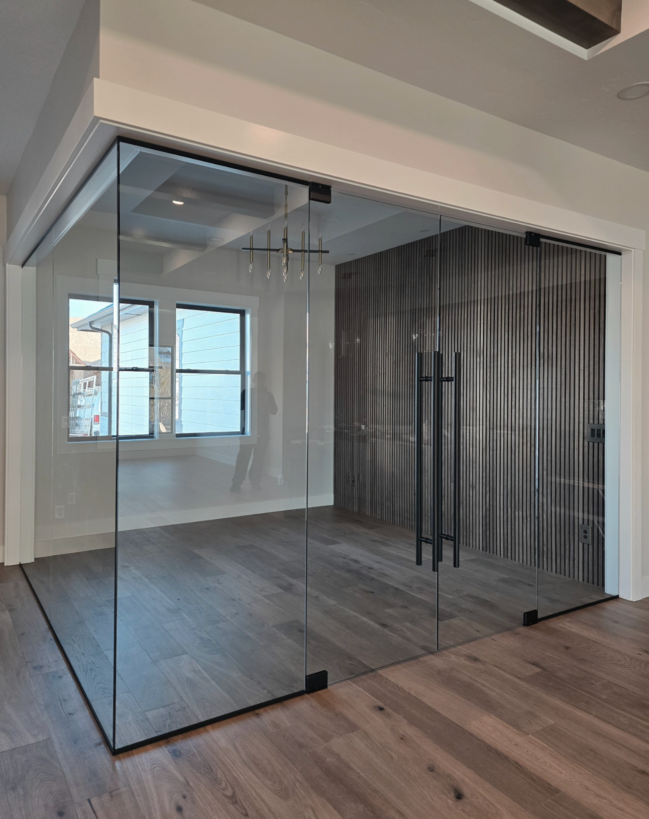 Glass-walled room with wooden floors, a textured gray wall, and sliding glass doors.