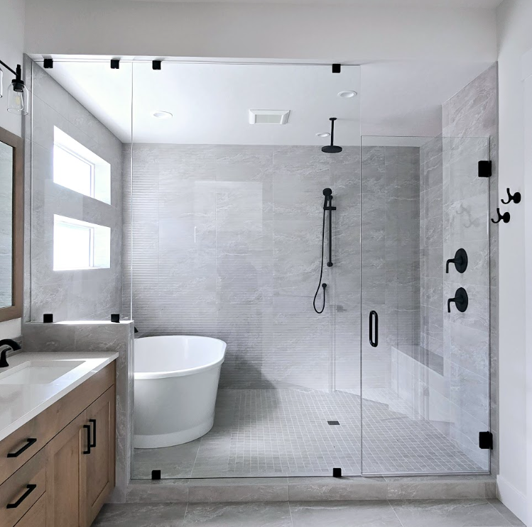 Modern bathroom with glass shower, freestanding tub, and light gray tile finishes