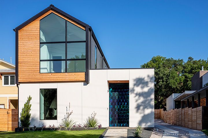 Modern house with a large glass window, light wood siding, and white exterior.