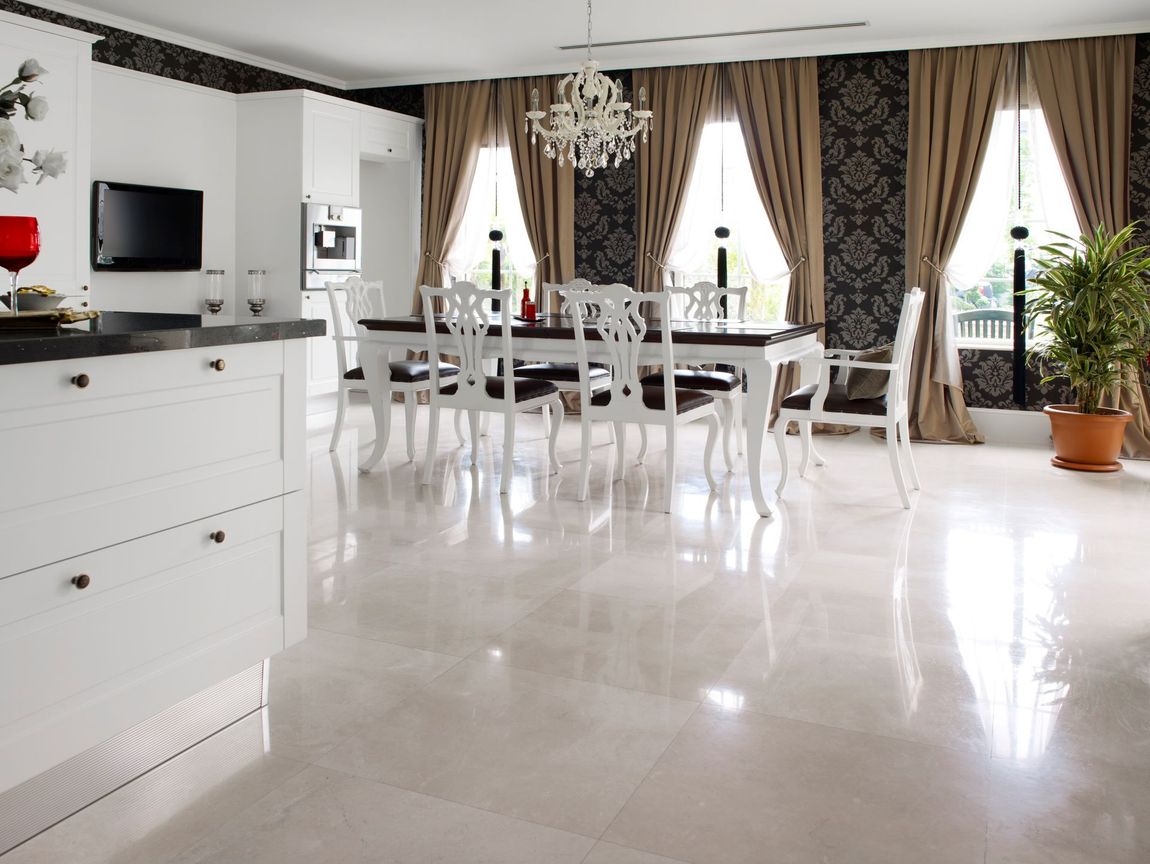 Kitchen and dining area with white cabinets, table, and shiny floor. Dark patterned curtains and chandelier.