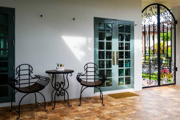 Patio with two chairs, small table, glass door, and ornate black gate.