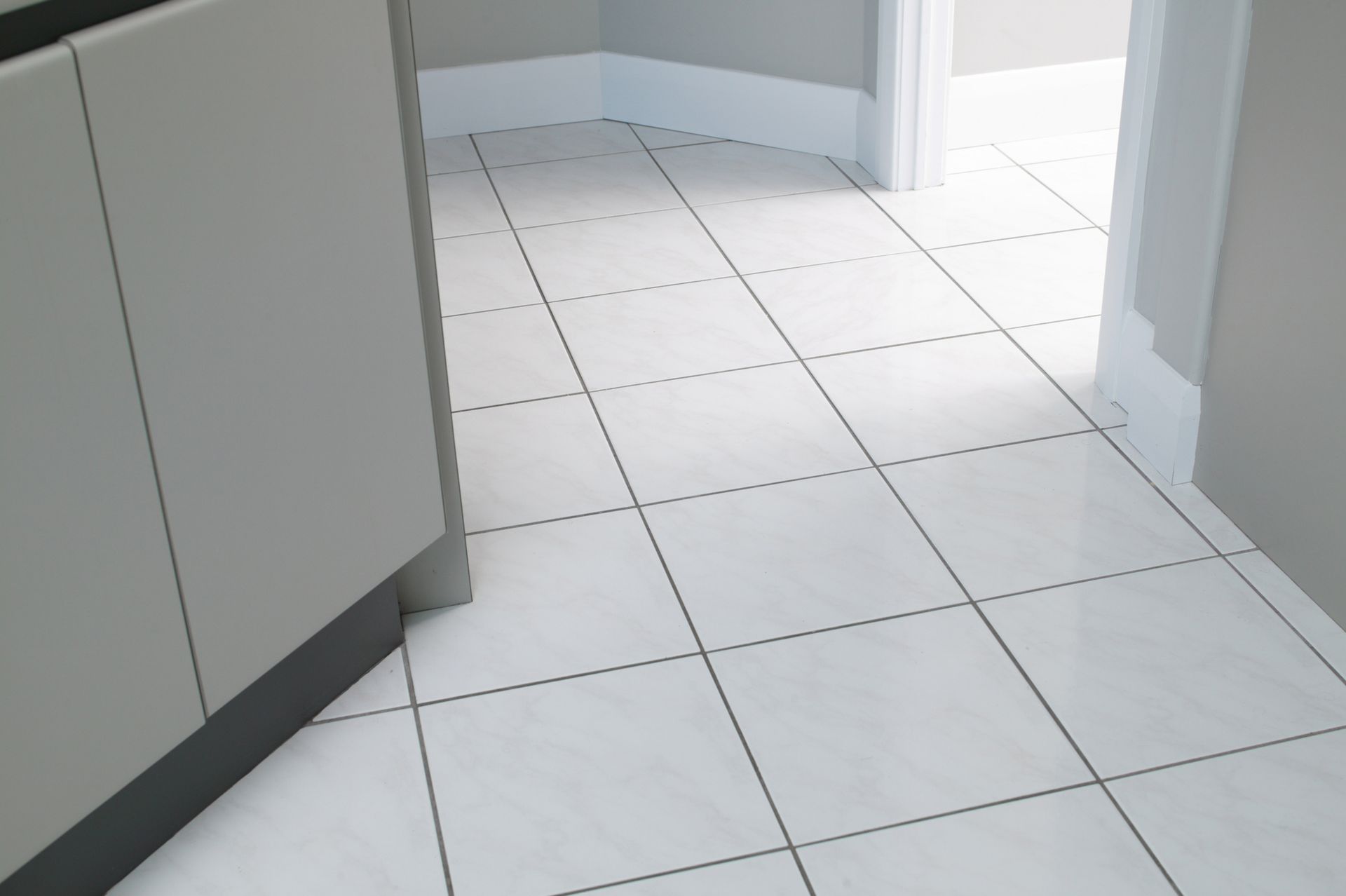 White tiled floor in hallway with a doorway.