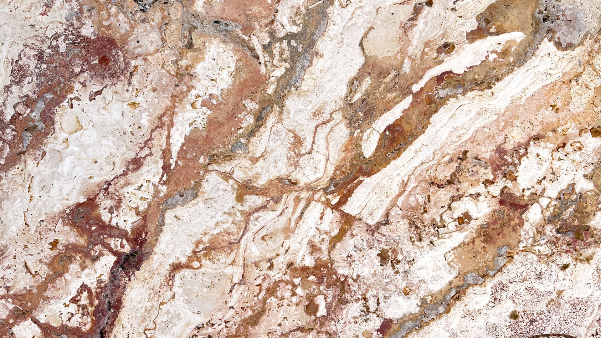Creamy stone surface with brown and reddish-brown streaks and speckles, resembling a marbled pattern.