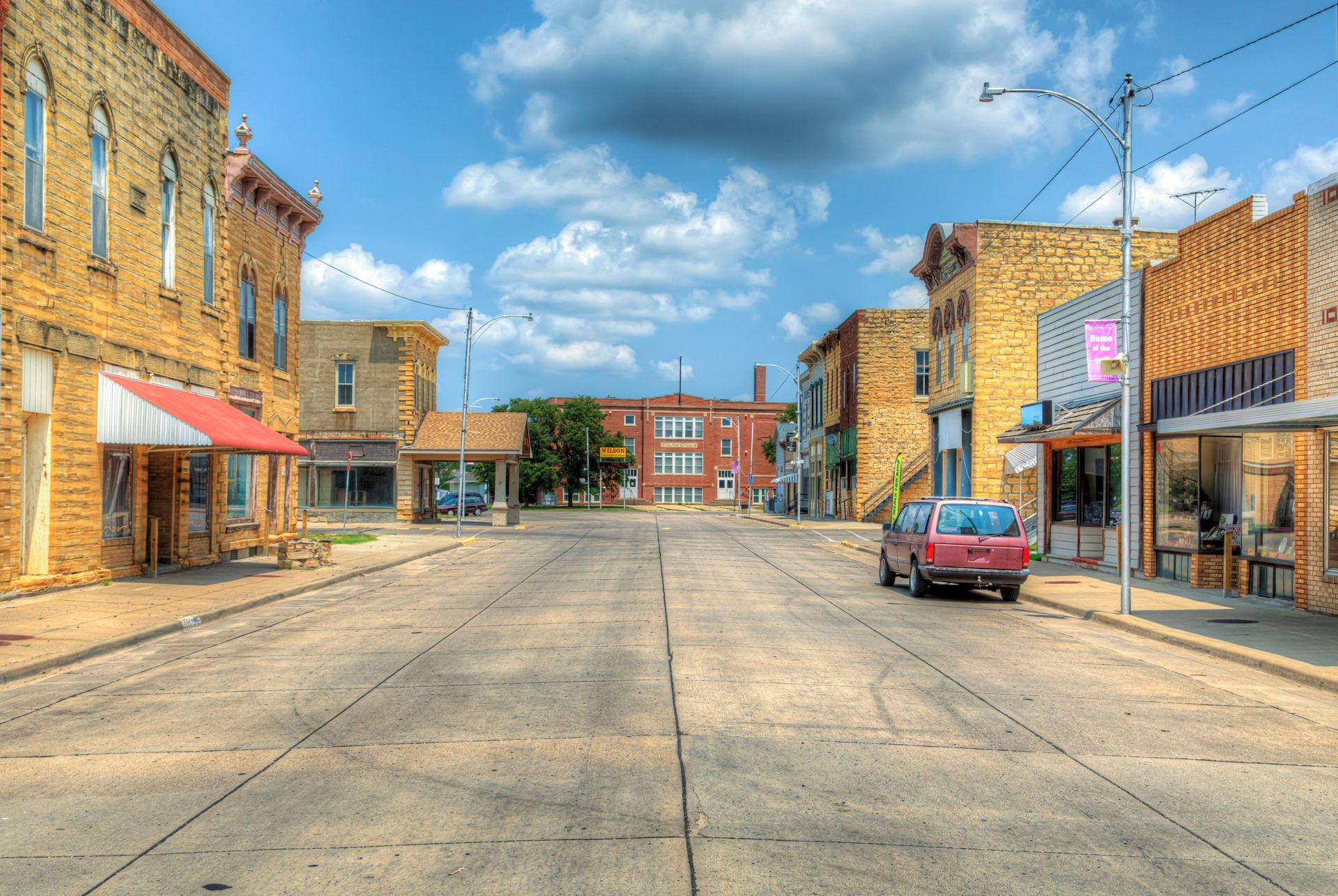Street in small town with old brick buildings, sunny day, blue sky, van parked.
