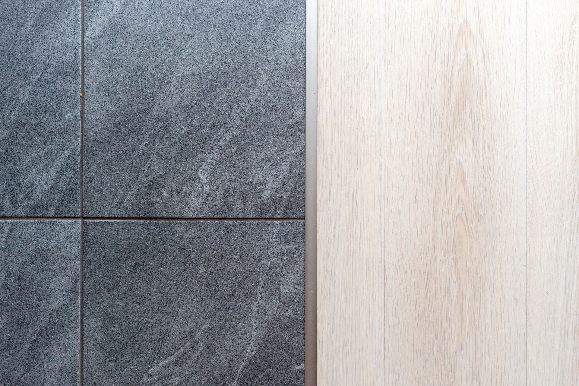 Gray tile floor next to light wood floor. Gray tile floor next to light wood floor.