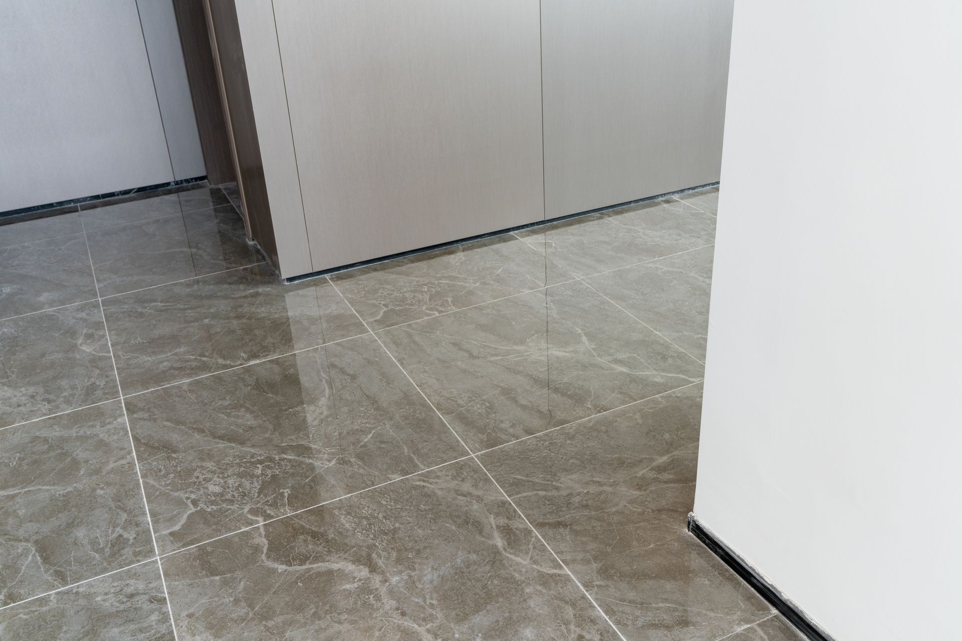 Gray marbled tile floor, a cabinet and white wall. Gray marbled tile floor, a cabinet and white wall.