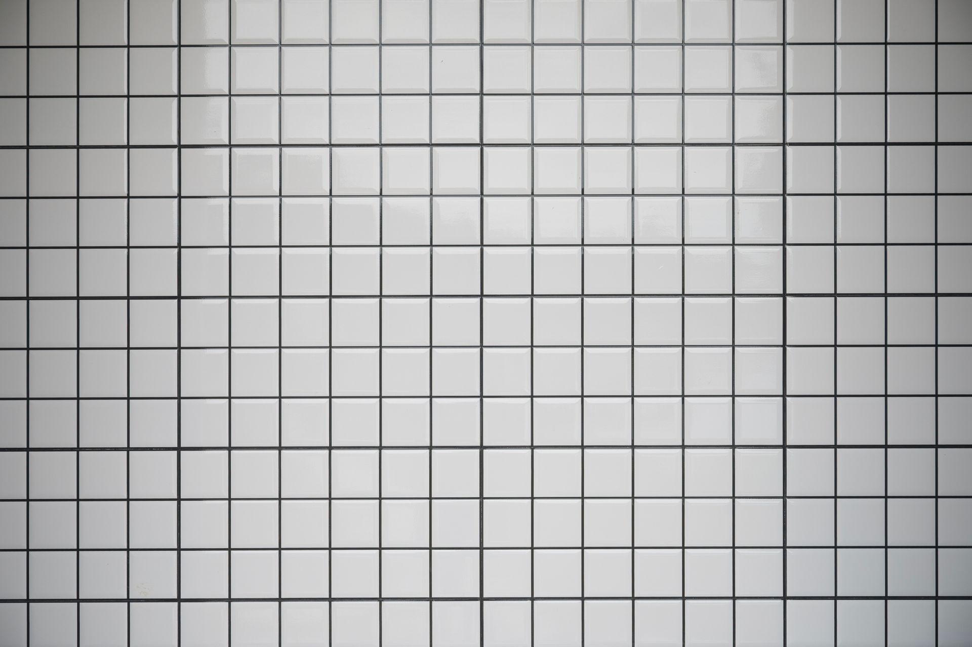 White square tiles on a wall, divided by dark grout lines.