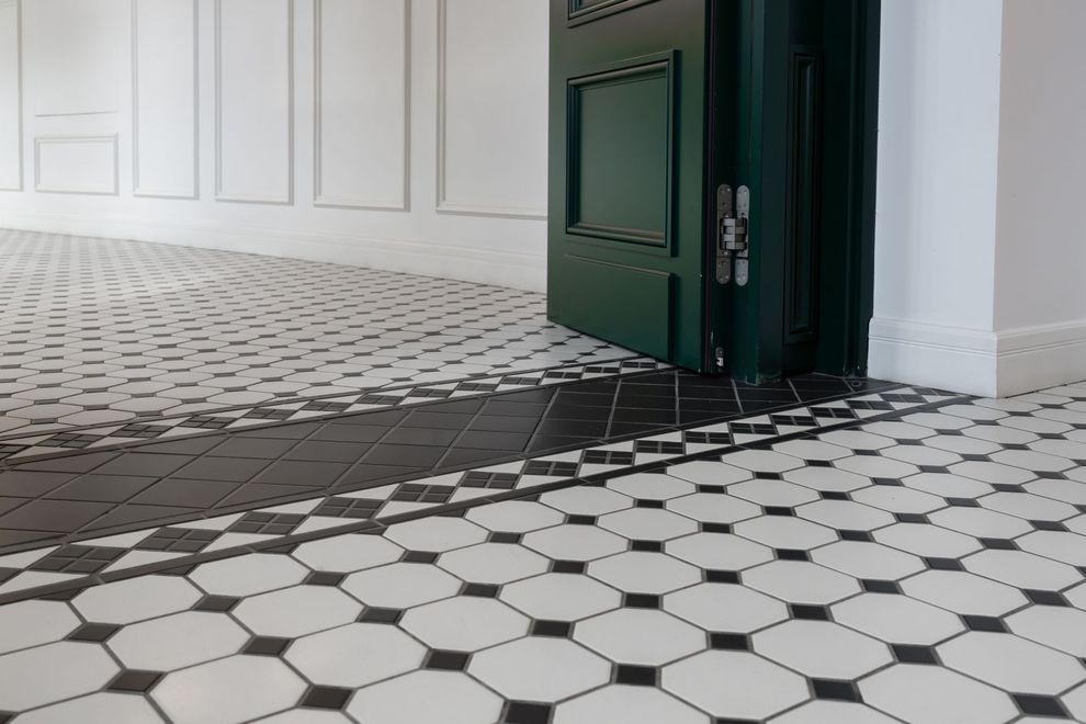 Black and white tiled floor with a black border, green door, and white walls.