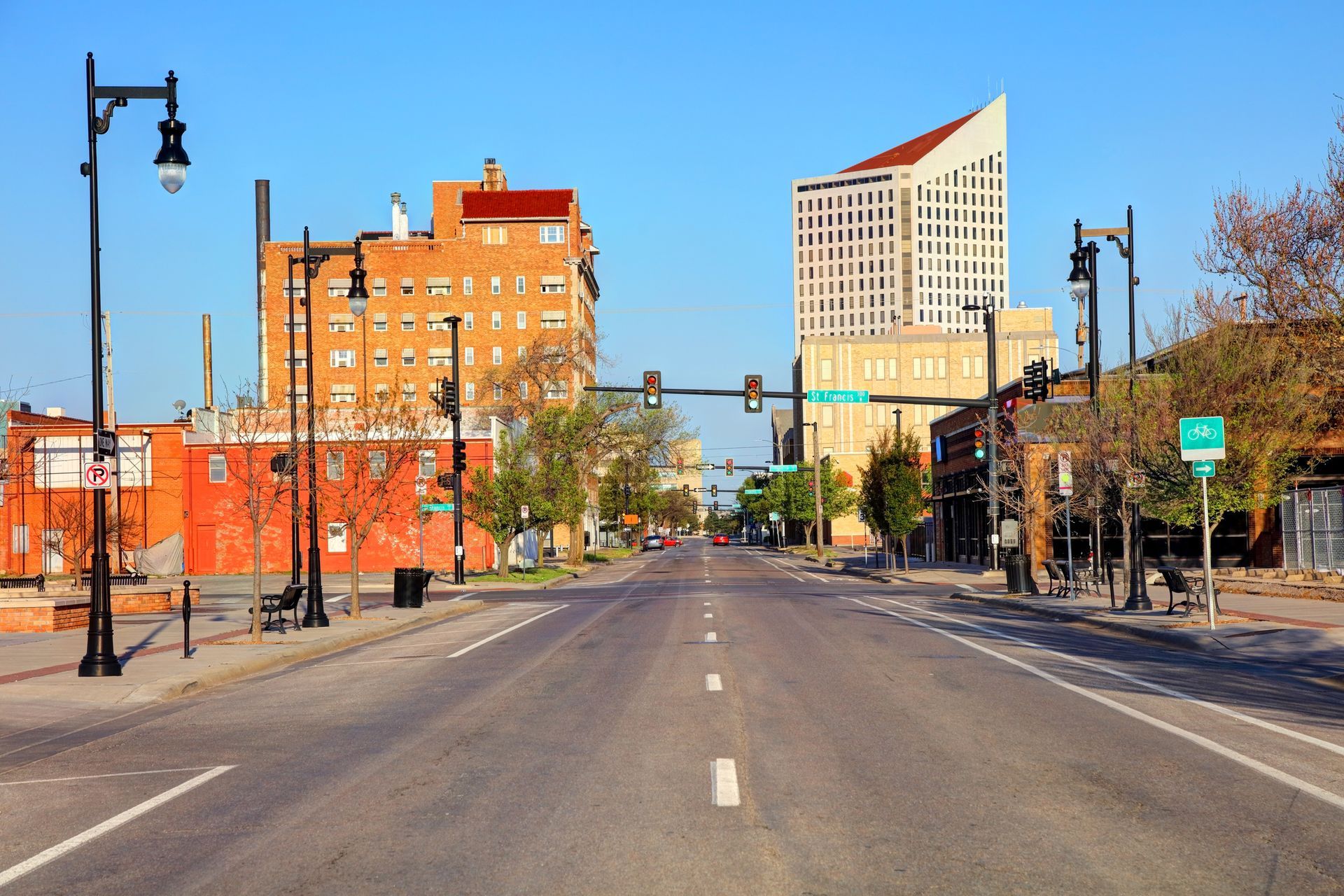 City street view with brick buildings and a tall modern tower under a blue sky.