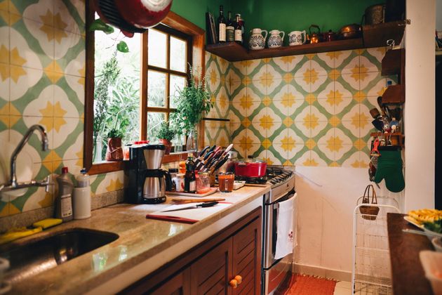 Kitchen with green walls, patterned tiles, wooden cabinets, window, sink, and stove.