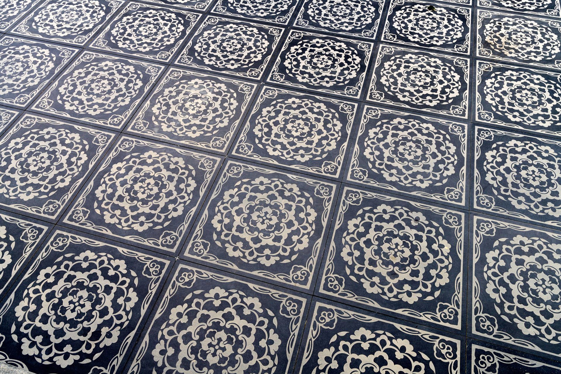 Dark tiled floor with ornate, circular, light-colored patterns within each square.