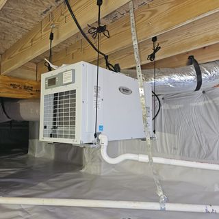 A white box is hanging from the ceiling in a basement