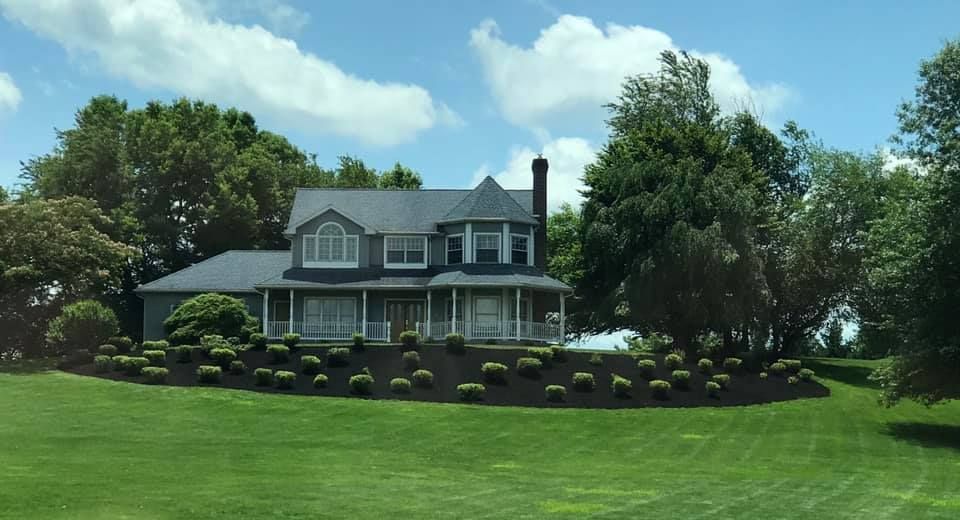 A large house sits in the middle of a lush green field