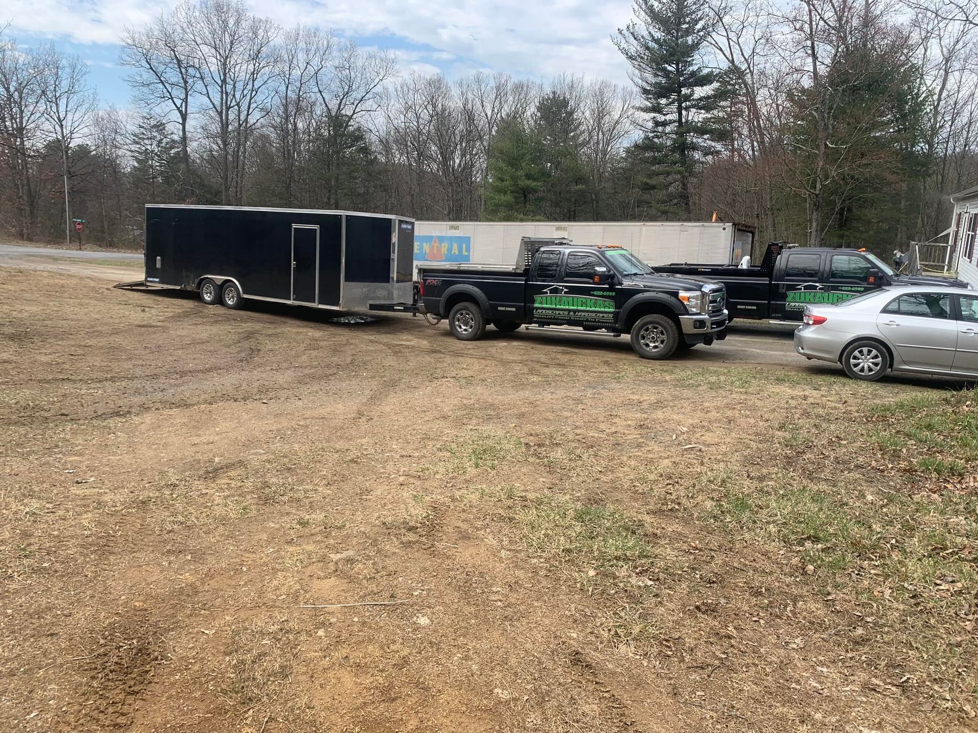 Two trucks and a trailer are parked in a field.