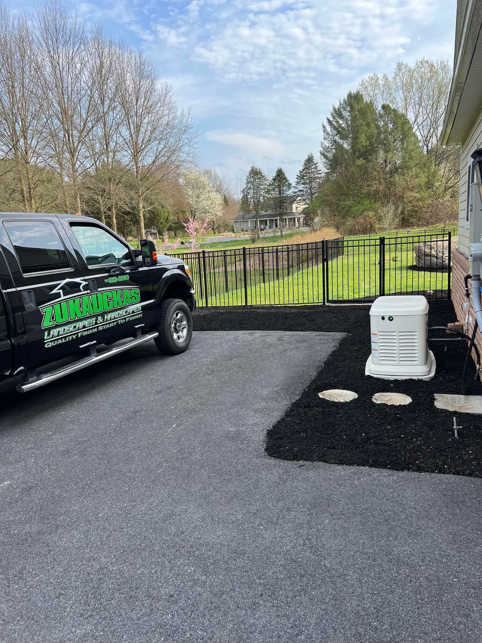 A black truck is parked in a driveway next to a house.
