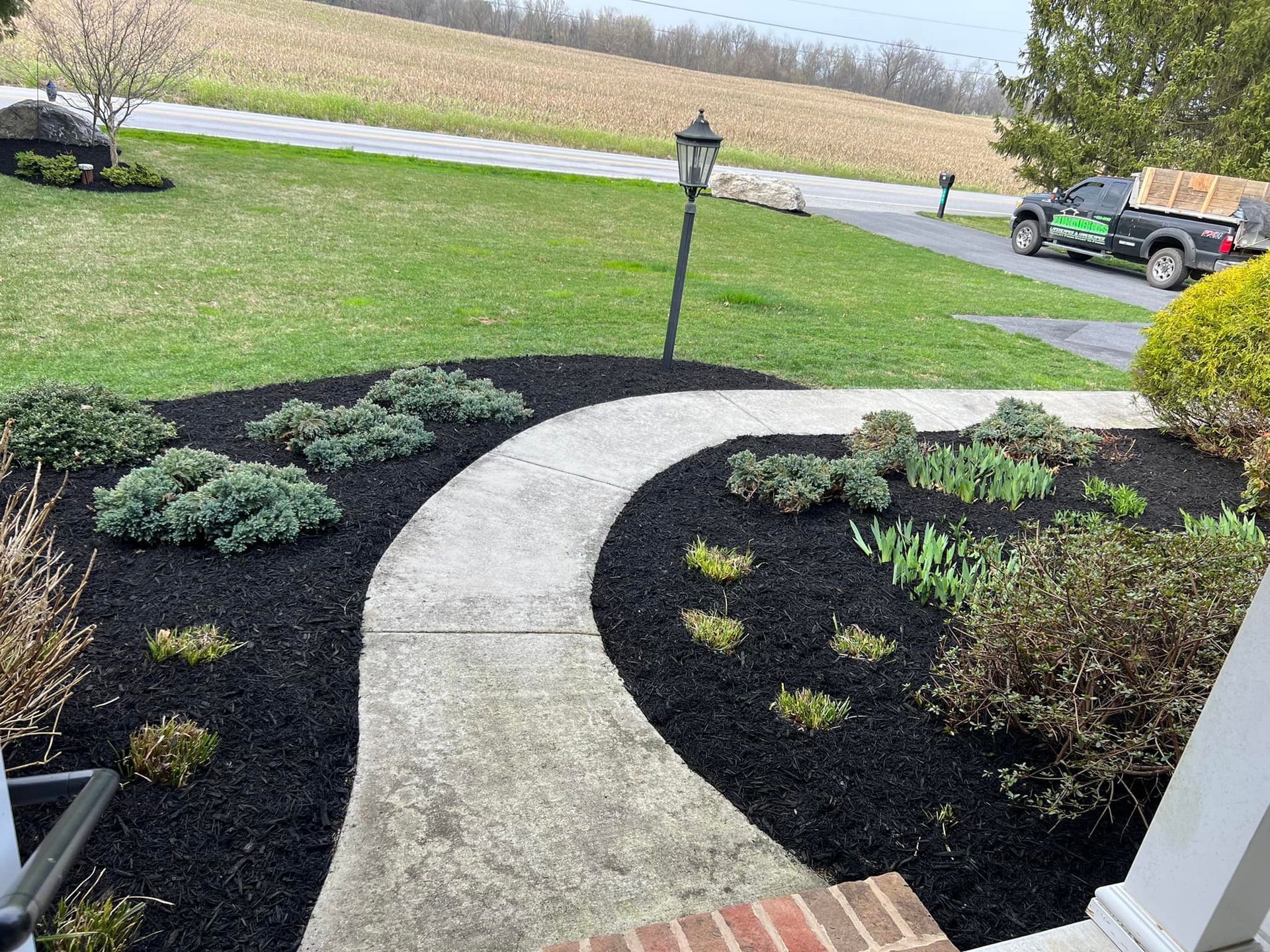 A walkway leading to a house with a car parked in the driveway.