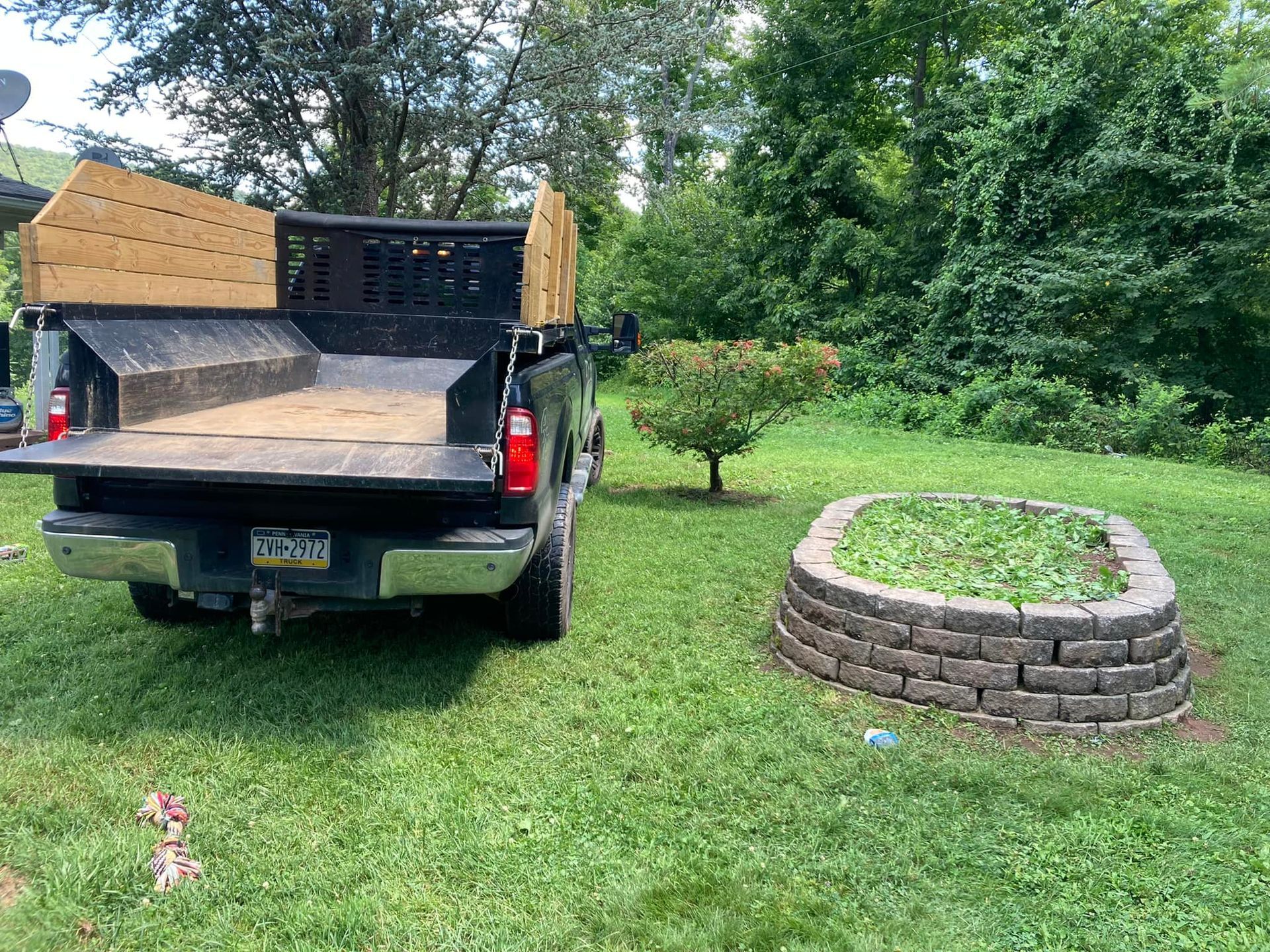A dump truck is parked in the grass next to a fire pit.