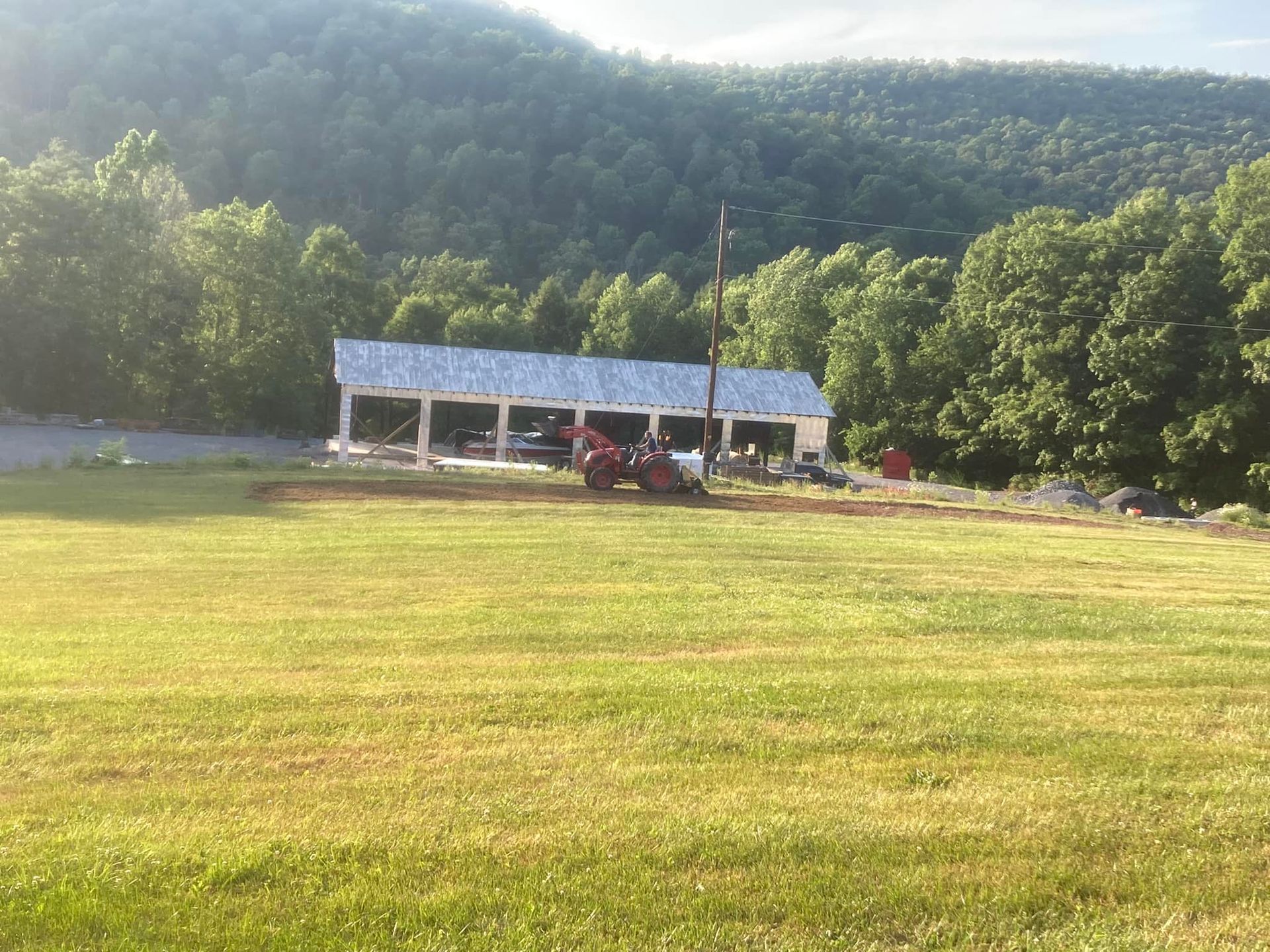 A tractor is cutting grass in a field in front of a building.