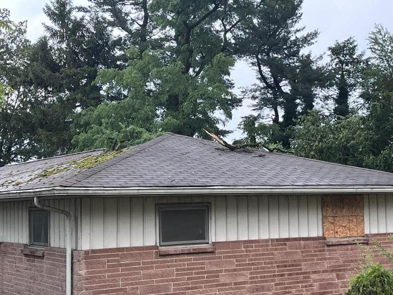 A brick house with a roof that has been damaged by a storm.