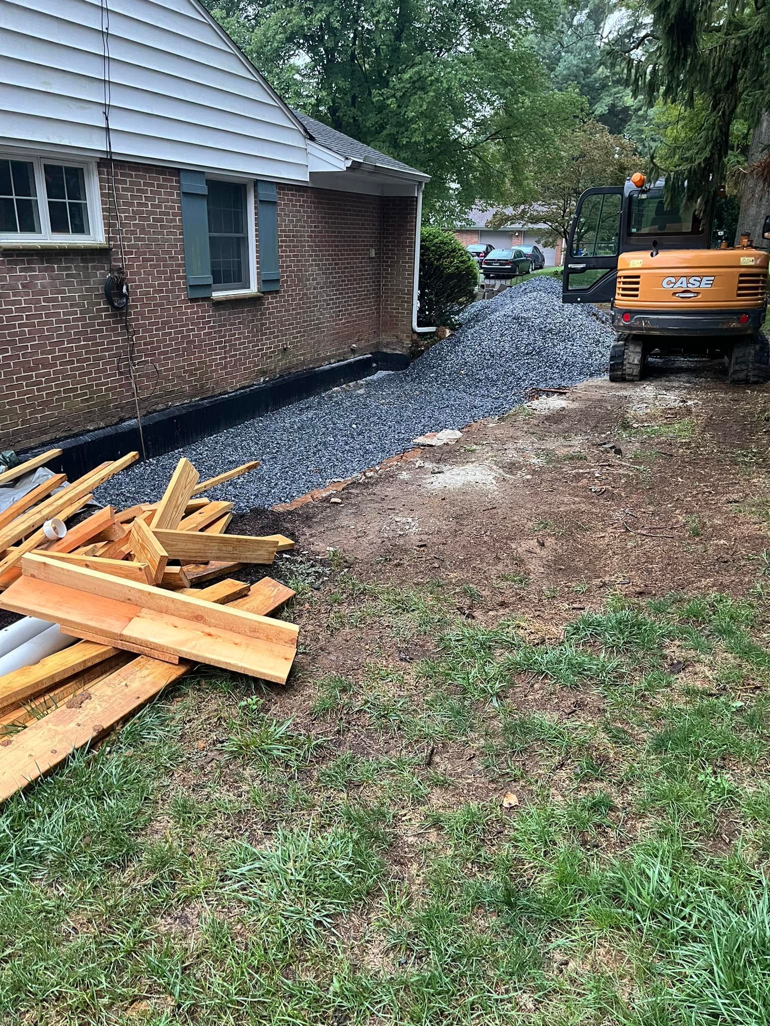 A pile of wood is sitting in the grass in front of a house.