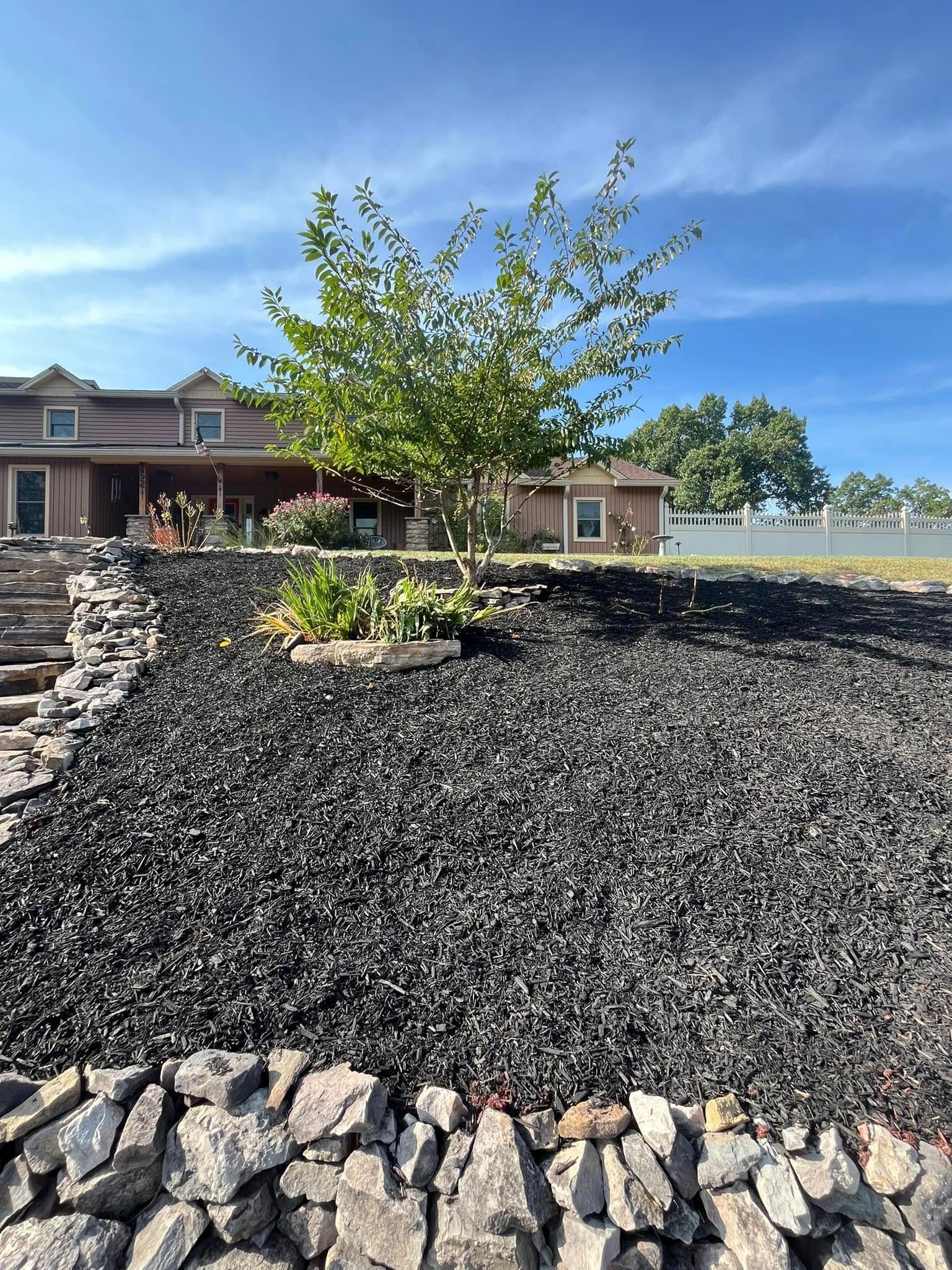 A large house is sitting on top of a hill next to a large pile of rocks.