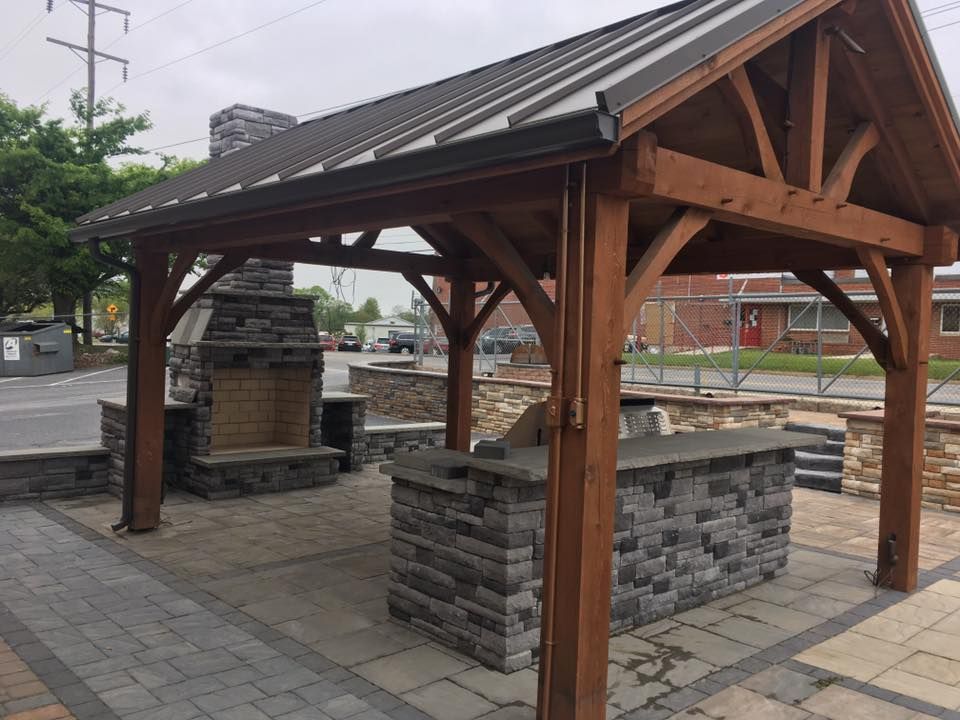 A wooden structure with a roof and a fireplace