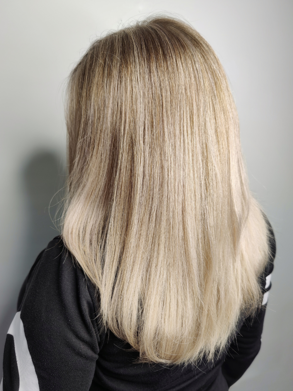 A woman with long blonde hair is wearing a black sweater.