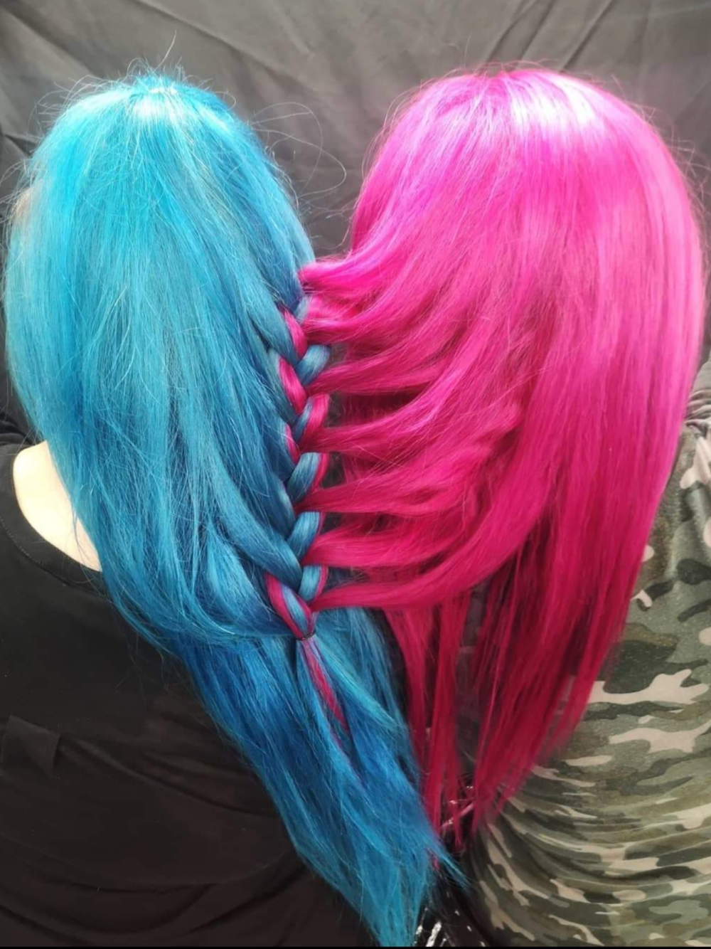 Two girls with blue and pink hair are sitting next to each other.