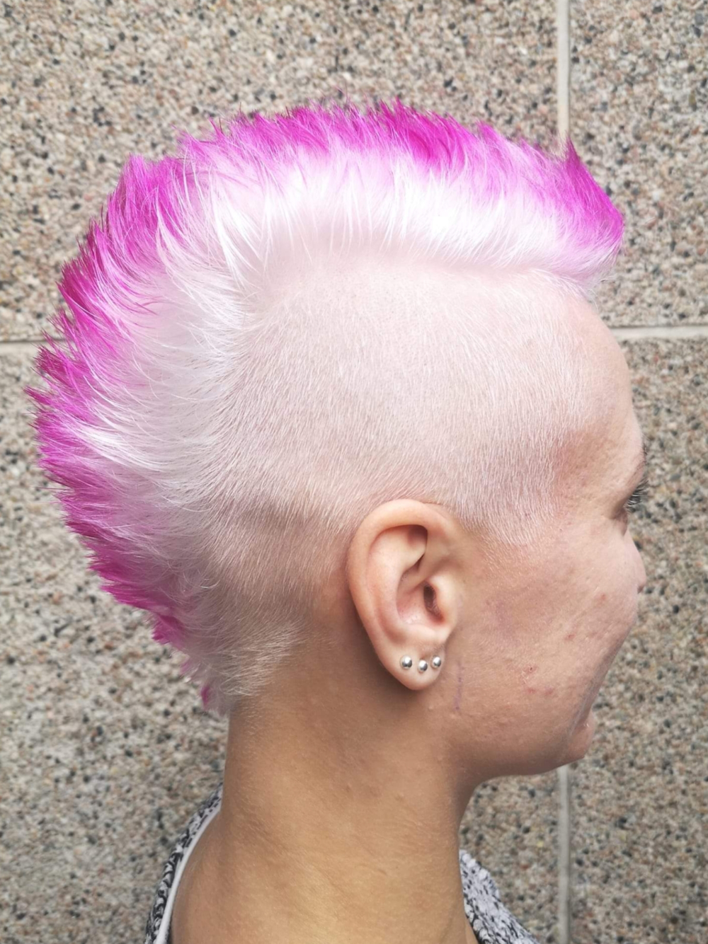 A woman with pink and white hair has a mohawk hairstyle