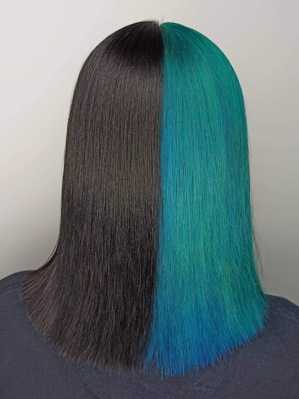 The back of a woman 's head with black and blue hair.