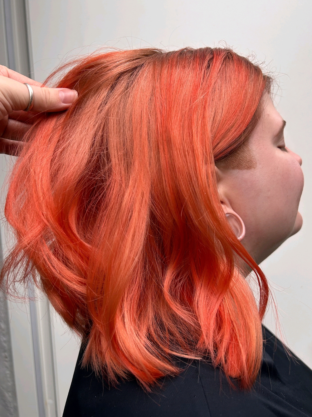 A woman with bright orange hair is getting her hair dyed.