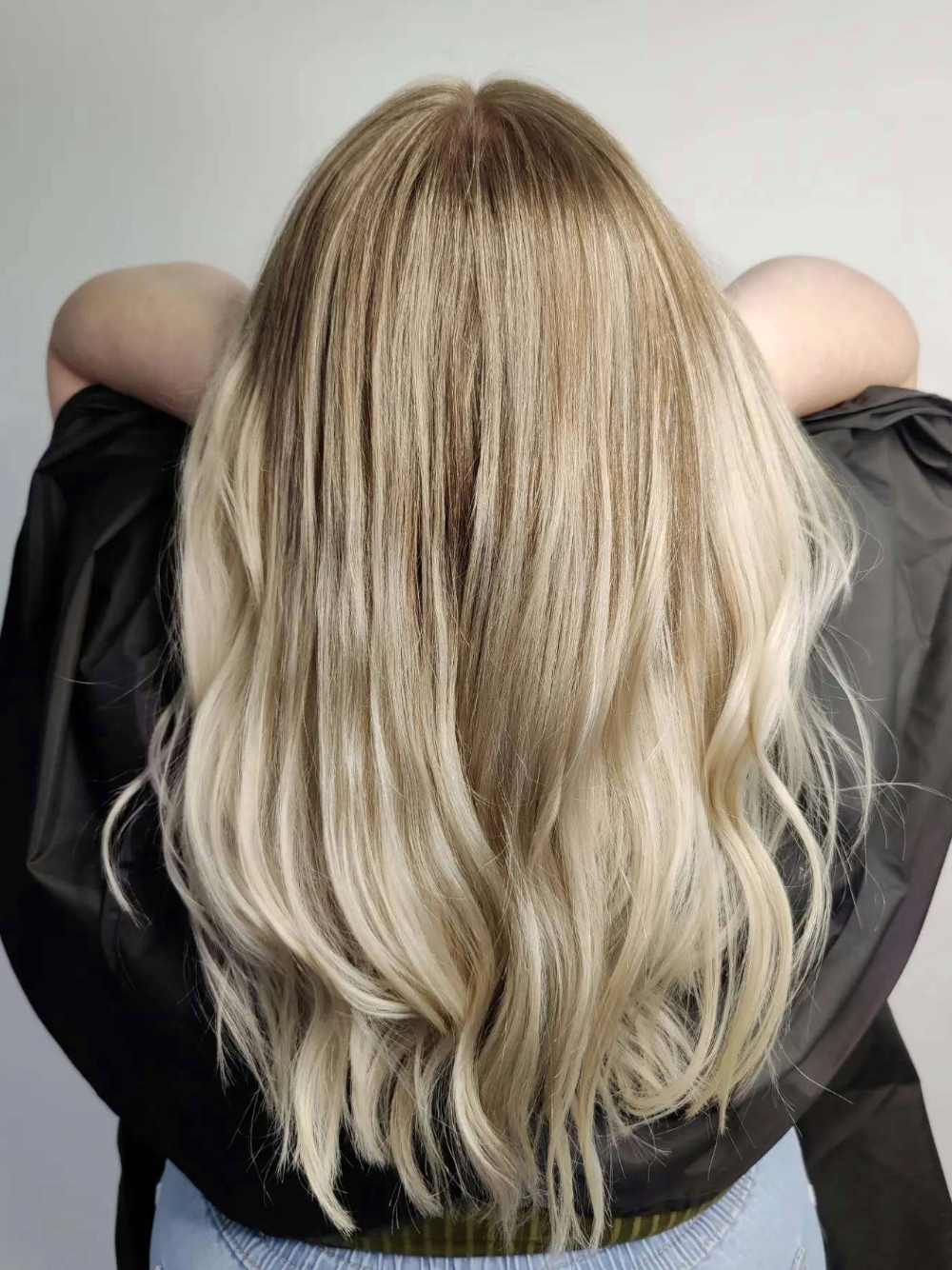 A woman with long blonde hair is wearing a black cape.