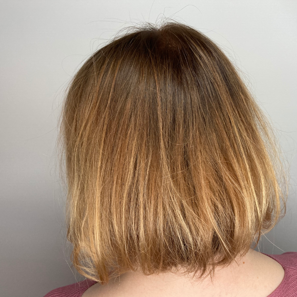 The back of a woman 's head with short blonde hair.