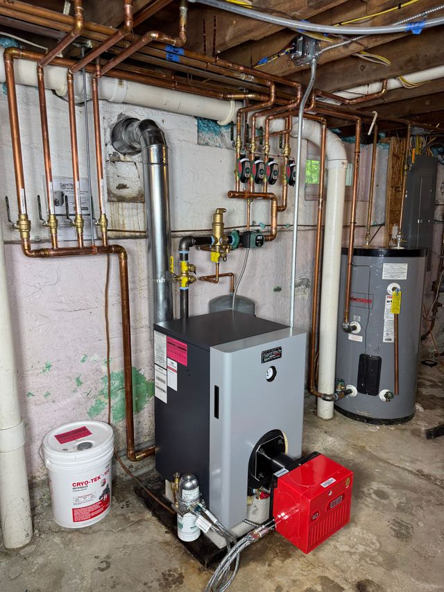 Basement utility room with gray water heater, furnace, copper pipes, and a red toolbox on the floor