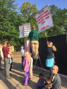 Protester’s 10 children stand guard as he lords over patients on a ladder.