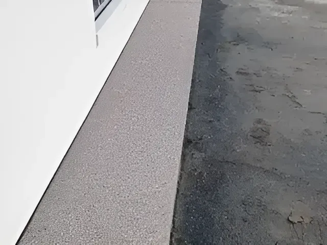 A White Building With A Black Sidewalk In Front Of It — S & K Gallaway Concreting In West Mackay, QLD