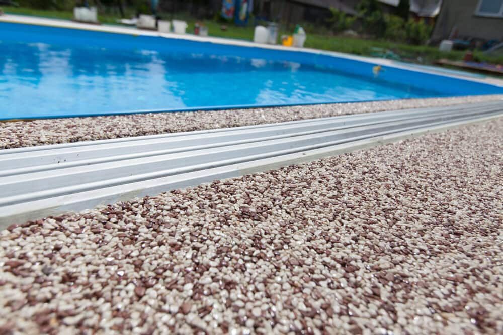 A Swimming Pool Surrounded By Gravel And A Metal Railing — S & K Gallaway Concreting In West Mackay, QLD