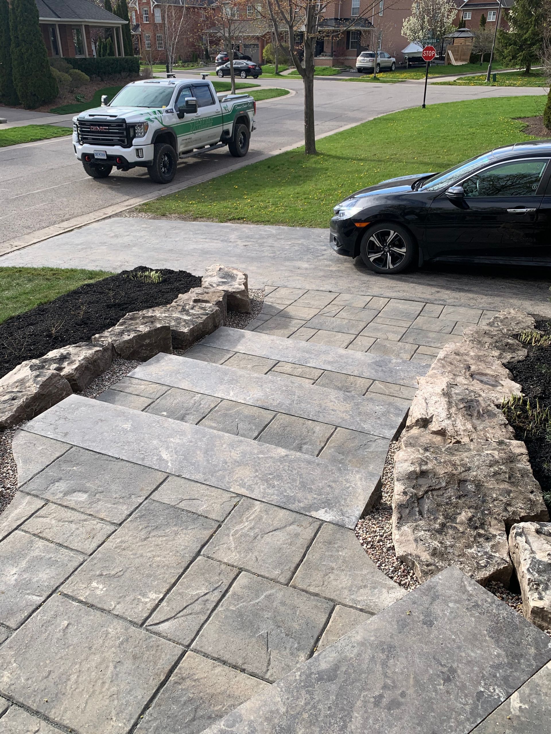 A white truck is parked on the side of the road next to a black car.