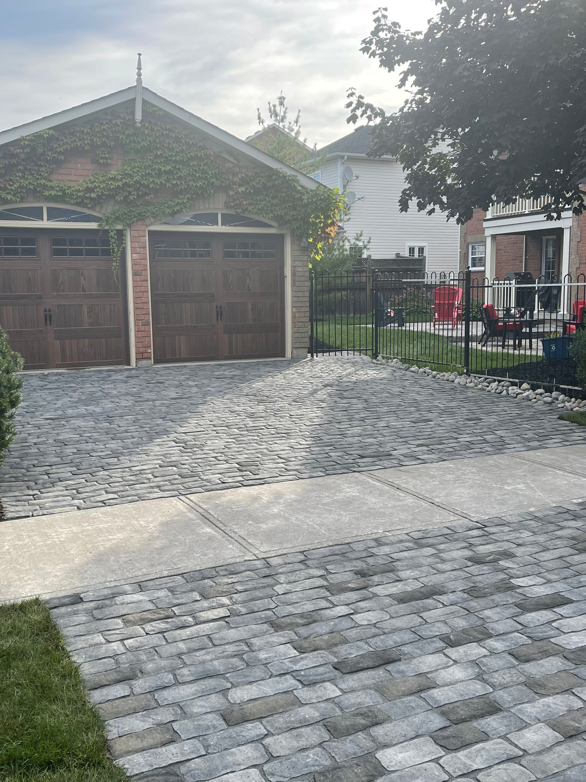 A brick driveway leading to a house with two garage doors