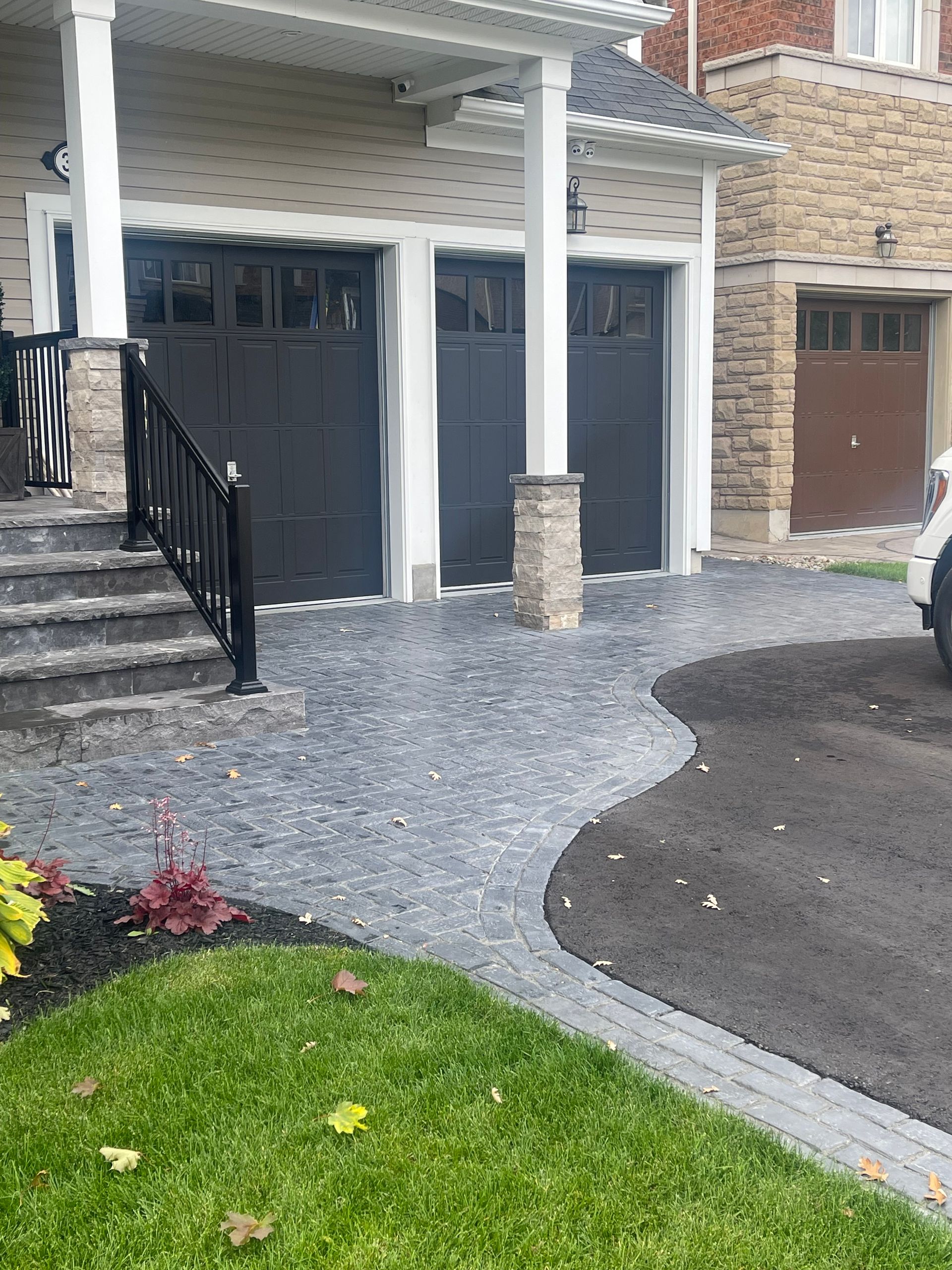A car is parked in front of a house with two garage doors.