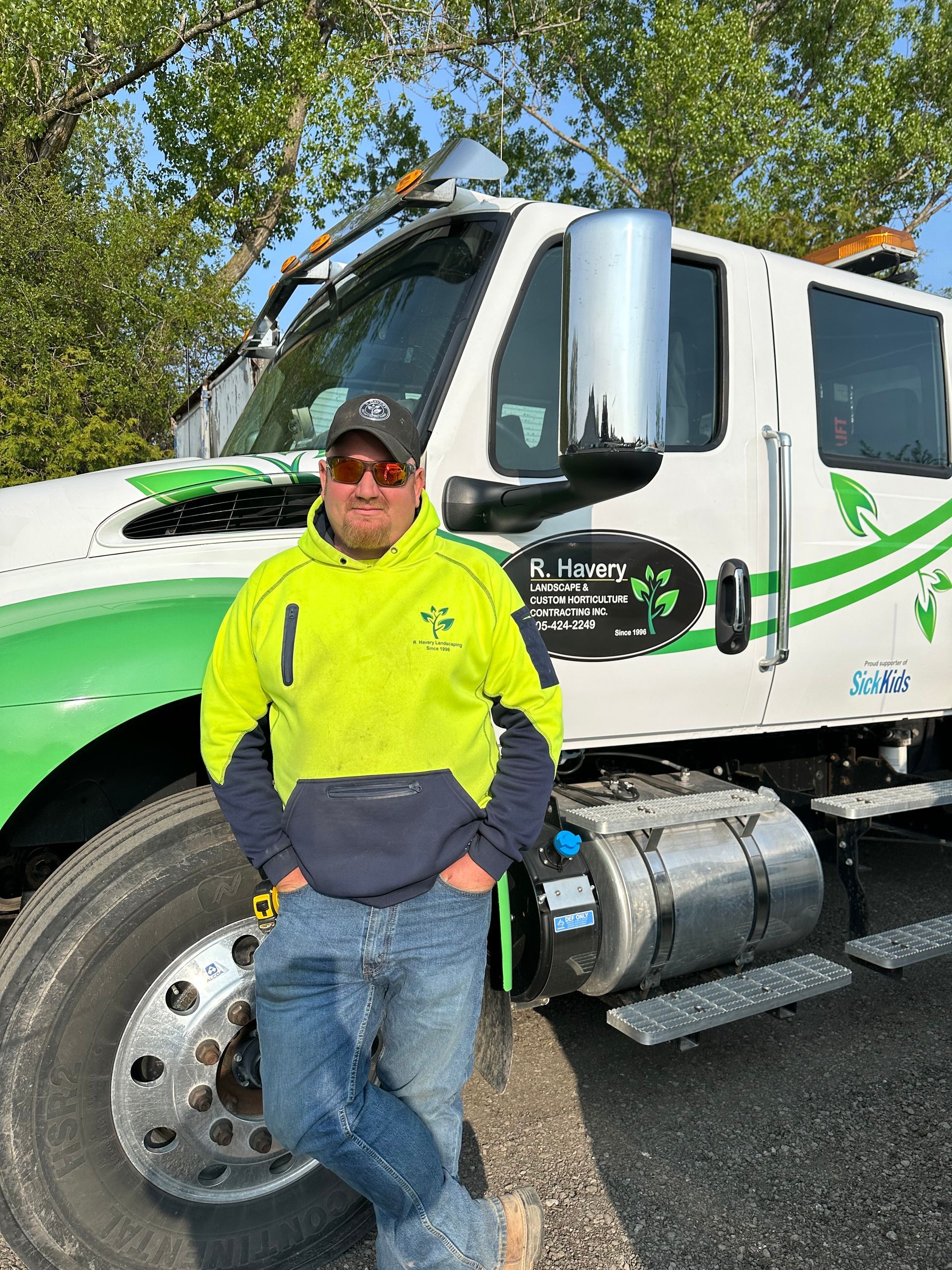 A man is standing in front of a green and white truck.