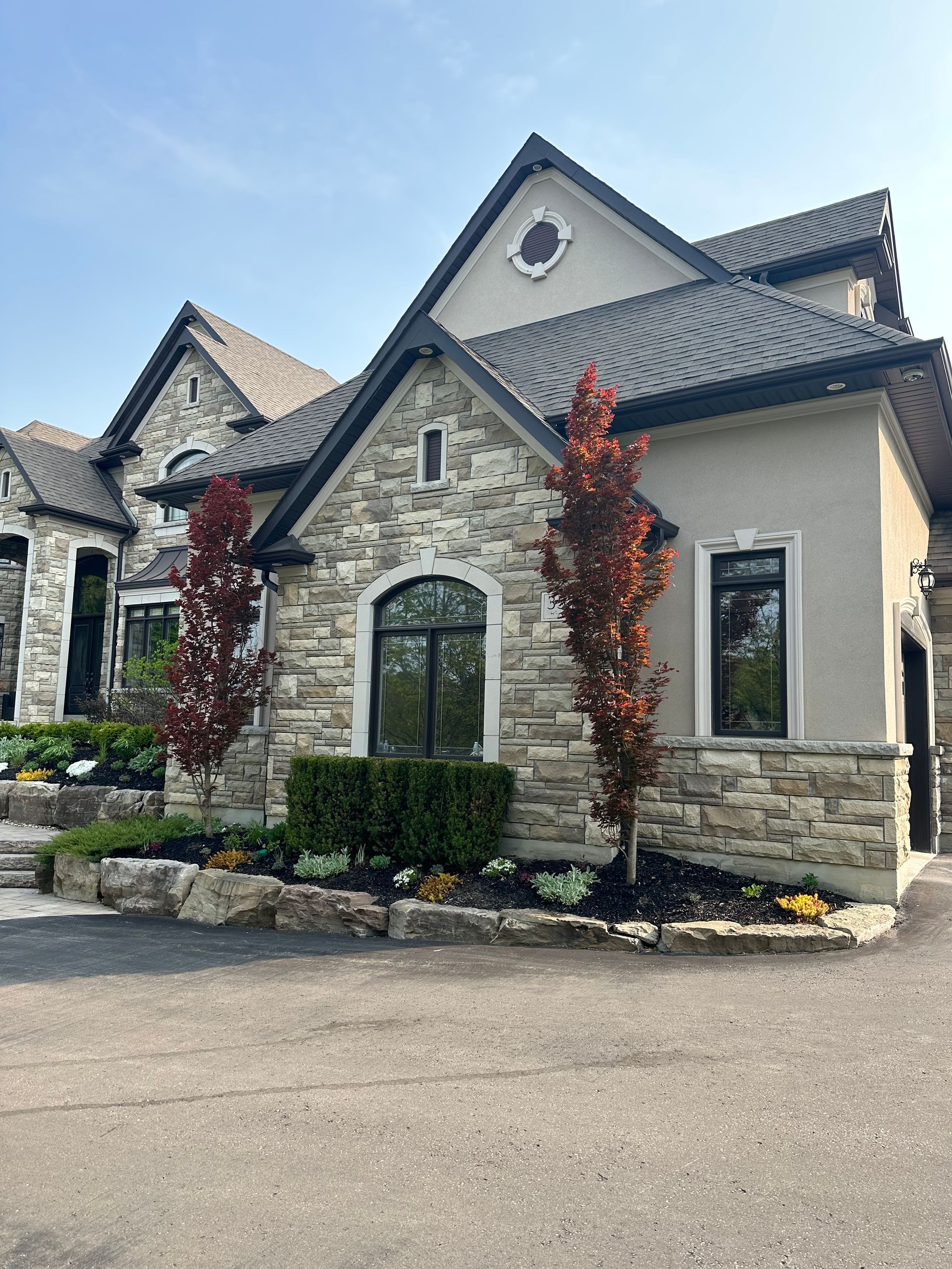 A large stone house with a black roof and a lot of windows.
