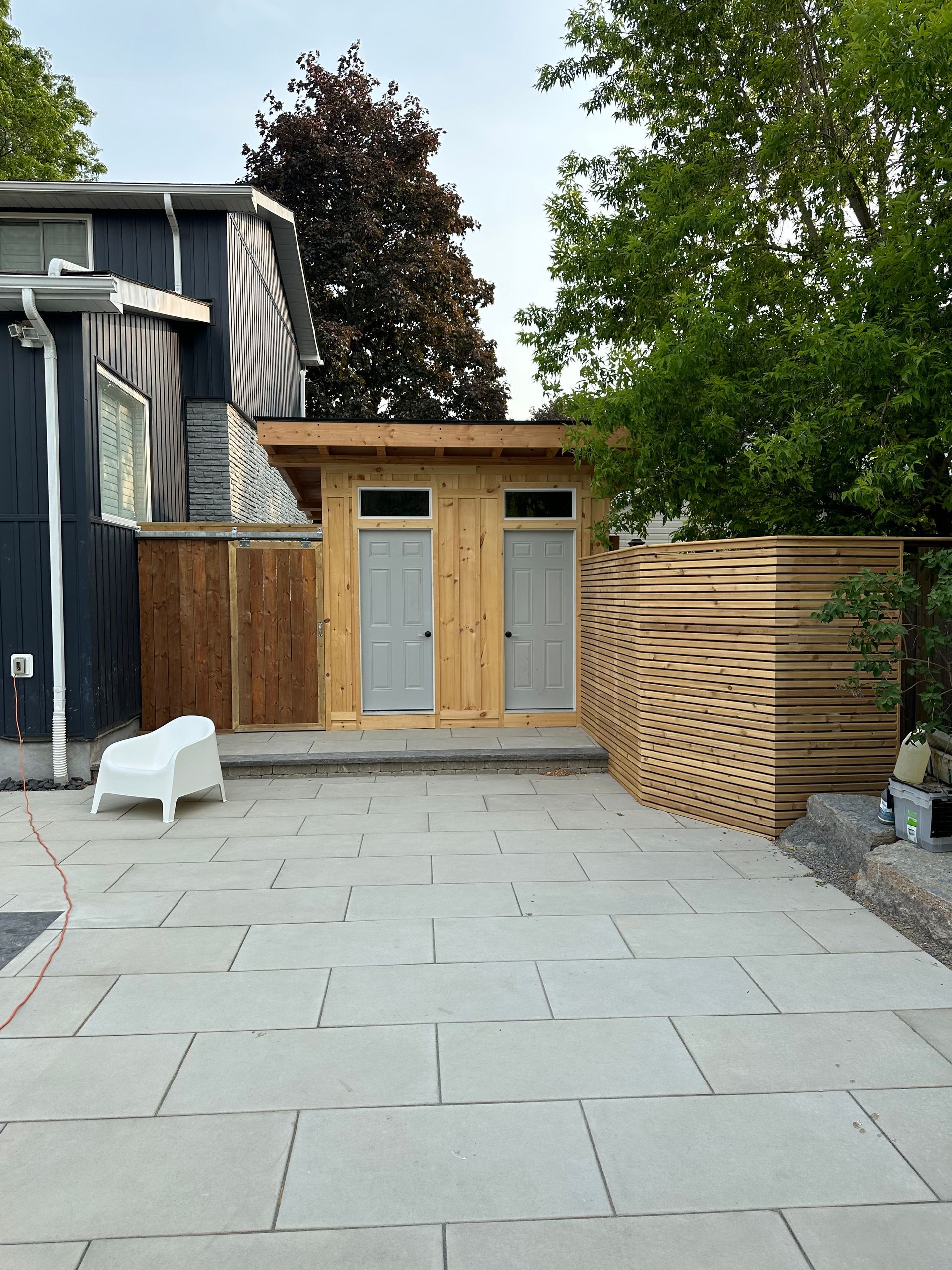 The backyard of a house with a wooden shed and a white chair