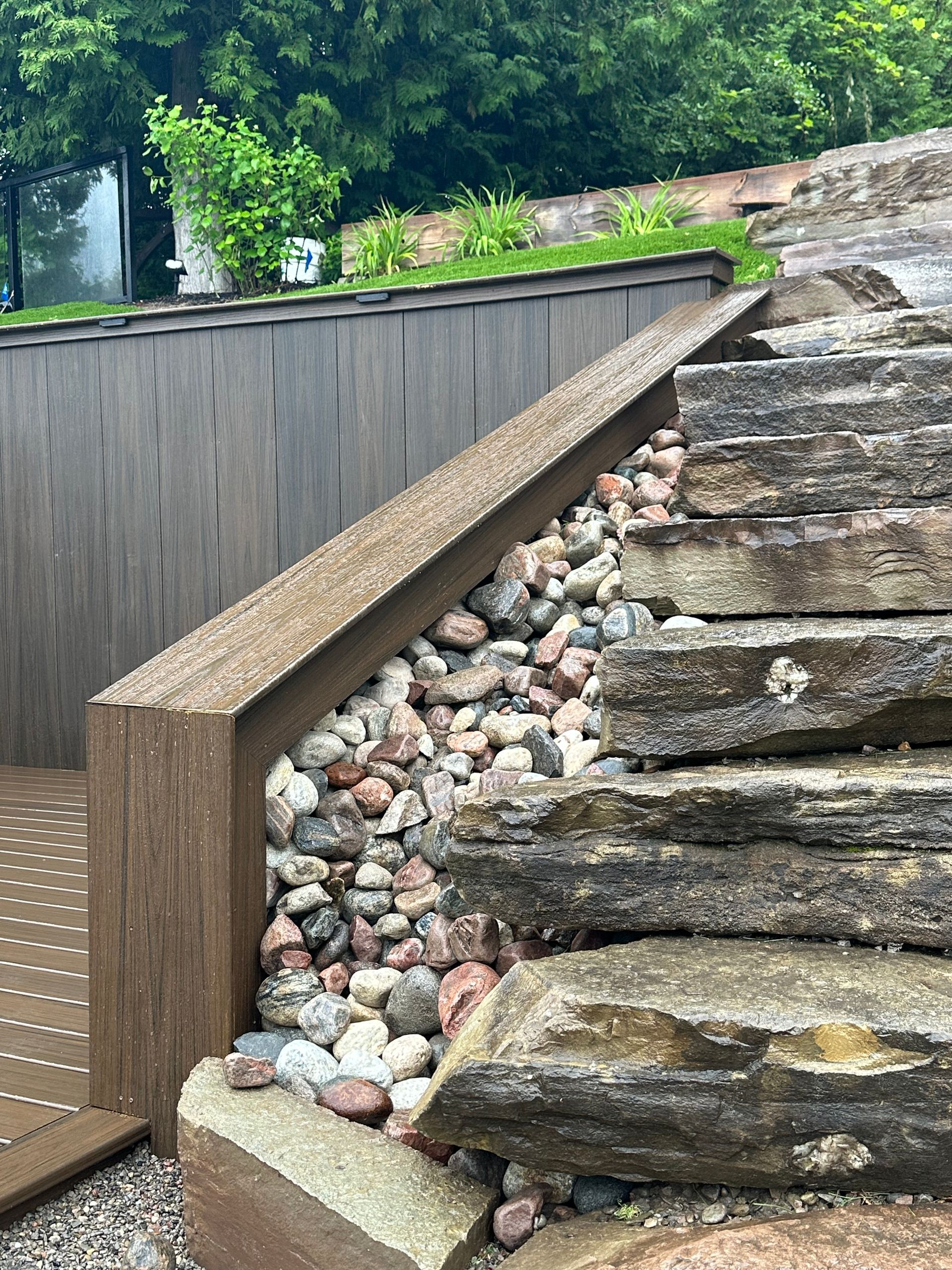 A stone staircase with a wooden railing surrounded by rocks and gravel.
