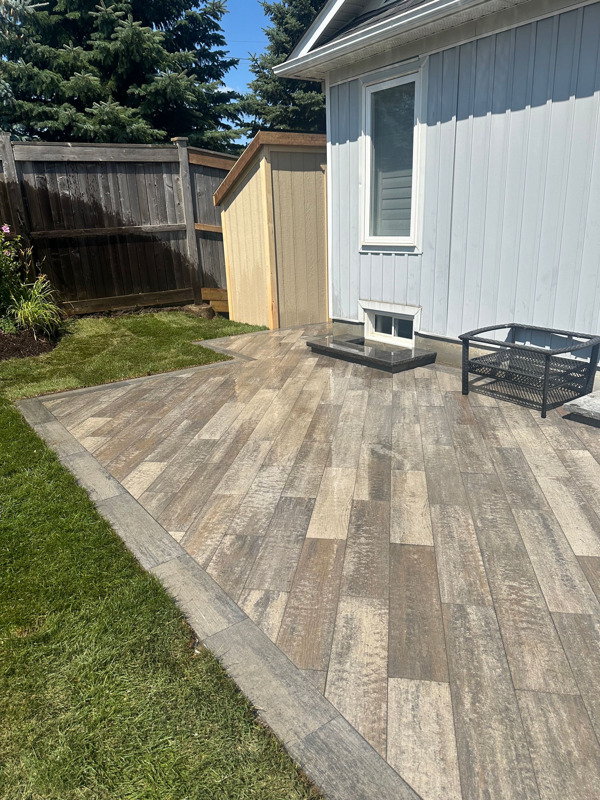 A patio with a shed in the backyard of a house.