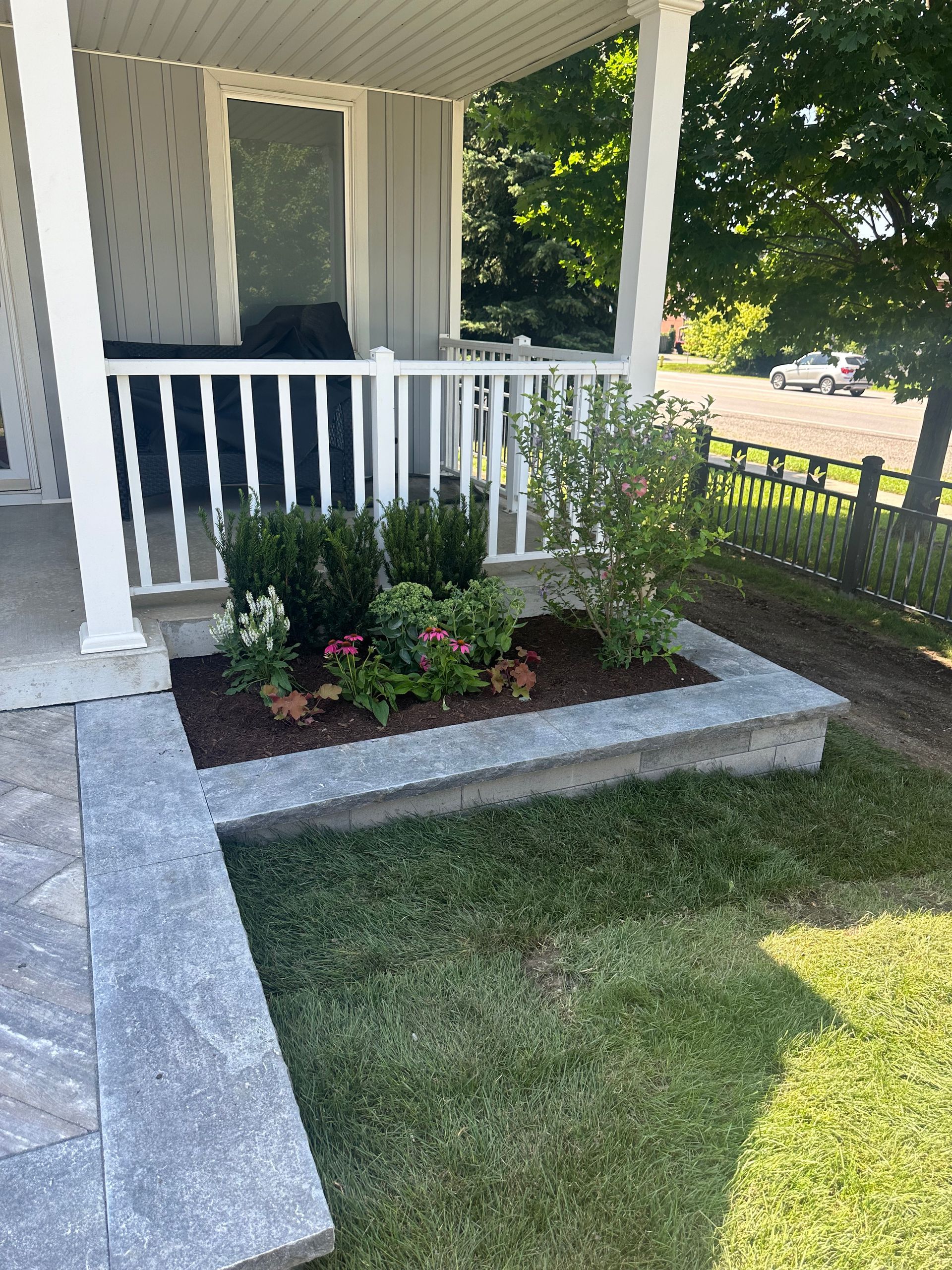 A porch with a planter of flowers in front of it.