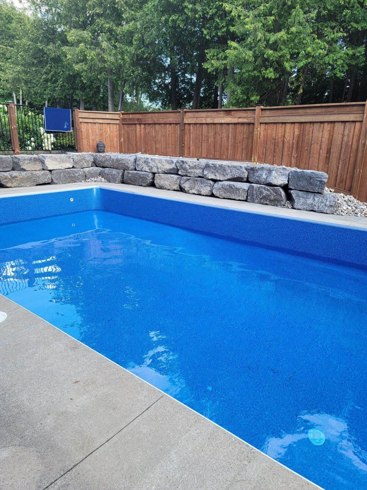 A large blue swimming pool with a wooden fence in the background