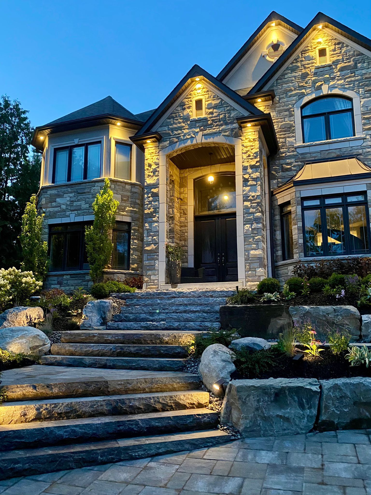 A large stone house with stairs leading up to it is lit up at night.