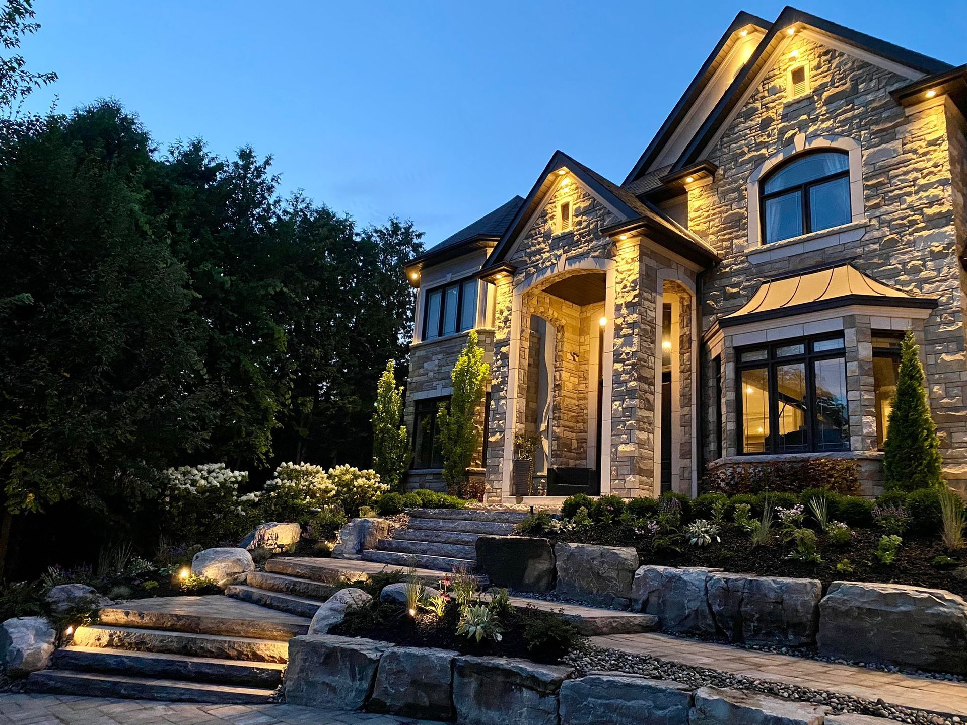 A large stone house with stairs leading up to it is lit up at night.