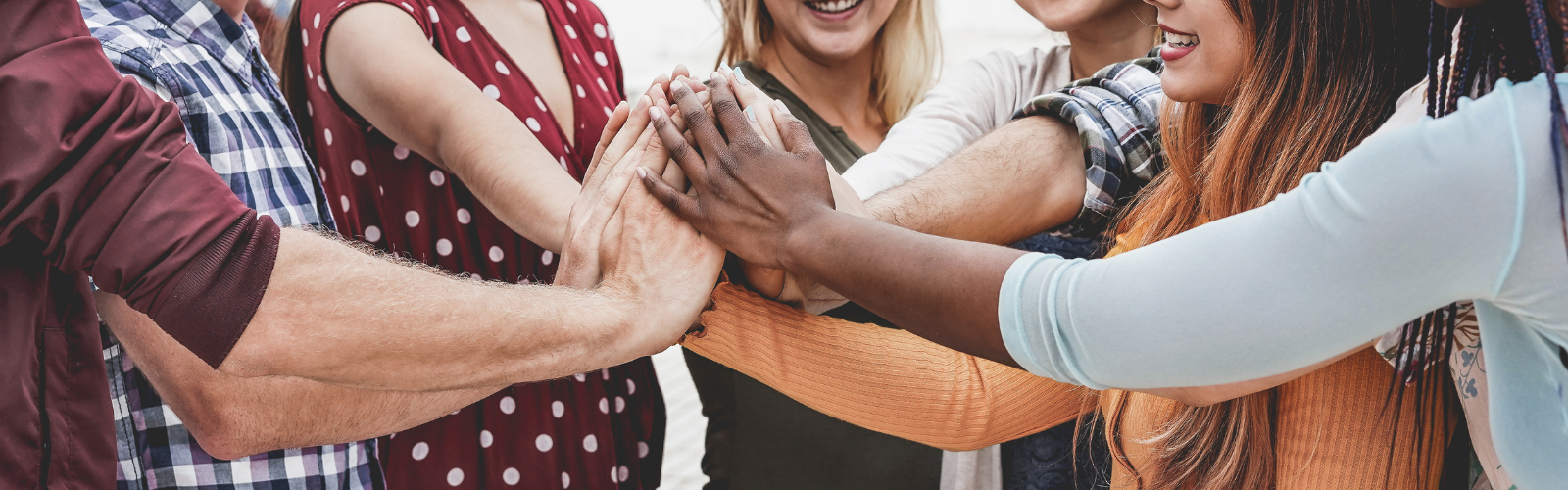 A group of people are putting their hands together in a circle.